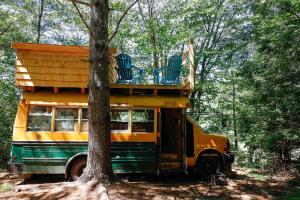 a bus with chairs on top of it parked next to a tree at Barn Door Hostel in Rumney