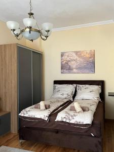 a bed in a bedroom with a chandelier at Alma - Panonia Apartments in Novi Sad