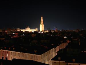 a view of a city at night with a clock tower at Vista Ghirlandina - Attico sul tetto del centro al settimo piano in Modena +37 photos