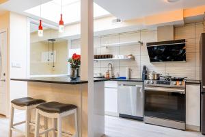 a kitchen with stainless steel appliances and black counter stools at Spacious 3BR Oasis with Patio & Arcade Fun in Philly in Philadelphia