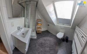Un baño blanco con lavabo y ducha. en Fuhrmannshof Ferienwohnung Amke, en Juist 10 fotos más