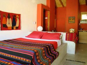 Un dormitorio con una cama con una manta colorida encima. en Posada La Valentina, en Villa Las Rosas