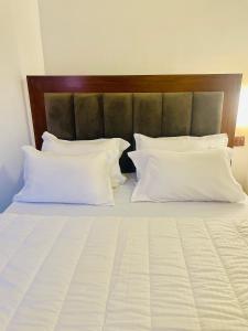 a large bed with white pillows and a wooden headboard at Vivid Colombo in Colombo