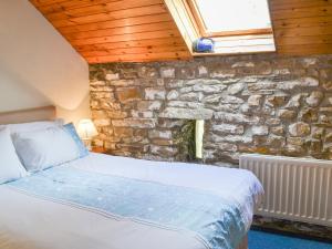 Bett in einem Zimmer mit einer Steinmauer in der Unterkunft Yarker Lane Cottage in Mickleton