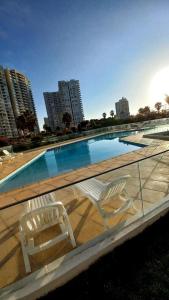 a white chair sitting next to a swimming pool at Hermoso departamento en Serena a pasos de la playa y casino in Coquimbo