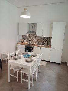 a white kitchen with a white table and chairs at Casa San Nicolò in Scicli