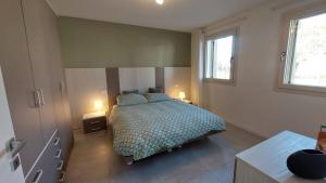 a bedroom with a bed and two tables and two windows at Appartamento La Bussola in Còvolo
