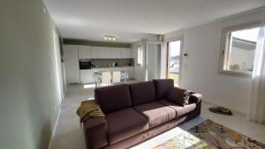 a living room with a brown couch and a kitchen at Appartamento La Bussola in Còvolo