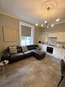 sala de estar con sofá de cuero negro y cocina en Springbank Apartment, en Aberdeen