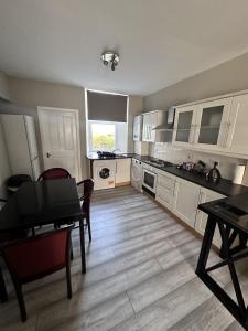 a kitchen with white cabinets and a table and chairs at Great Northern Apartment in Aberdeen