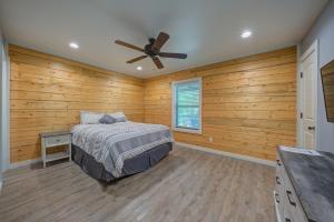 a bedroom with wooden walls and a bed and a ceiling fan at Happy Times on Caddo River by StayLage in Glenwood
