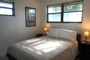 a bedroom with a bed with two lamps and two windows at Firethorn Paradise - Family Friendly Fun Near the Beach, Dogs Welcomed in Gulf Breeze