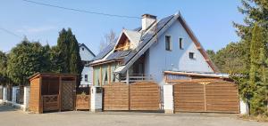 una casa bianca con porte da garage in legno di fronte di 'PRZY PARKU' pokoje gościnne u zielarki a Stegna