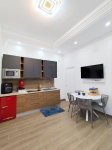 a kitchen with a table with chairs and a tv at Maria Grazia's House in Ercolano