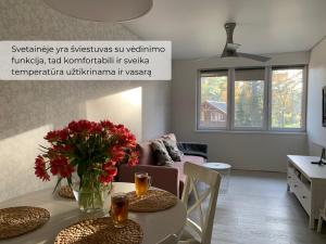a living room with a table with red flowers on it at Palūšės Apartment in Palūšė