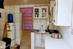 a small kitchen with white cabinets and a refrigerator at Temporada no Atalaia in Salinópolis
