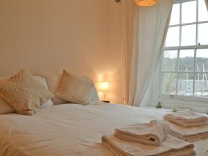 a white bed with towels on it with a window at Daisy Bank Cottage in Bowness-on-Windermere