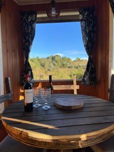 einen Holztisch mit einer Flasche Wein und Gläsern in der Unterkunft Chalé acima das nuvens - Serra da Bocaina in São José do Barreiro