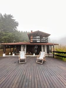 zwei Stühle auf einer Terrasse vor einem Haus in der Unterkunft Chalé acima das nuvens - Serra da Bocaina in São José do Barreiro