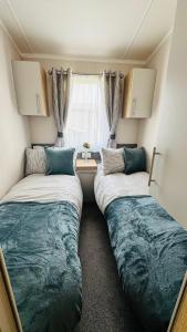 two beds in a small room with a window at Luxury 8 Berth Caravan At Butlins Skegness in Skegness