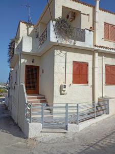 a white building with red shutters and a porch at Holiday House in Porto Heli