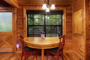 a wooden table and chairs in a room with a window at All Aboard - Log Cabin, Game Room, Hot Tub, Lake View, Private Dock - Blue Ridge, GA in Blue Ridge +19 photos