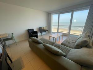 - un salon avec un canapé et une vue sur la plage dans l'établissement Westende Zeezicht, à Middelkerke