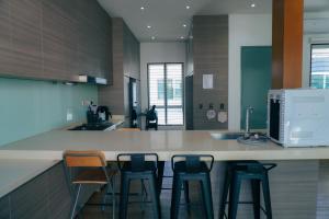 a kitchen with three bar stools and a microwave at Bandar Botanic Klang lux bungalow Home stay in Pelabohan Klang
