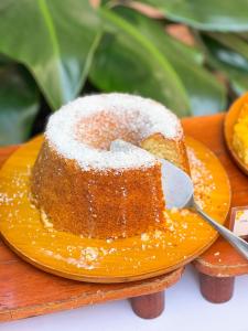 a piece of cake on an orange plate with a spoon at Castro's Park Hotel in Goiânia