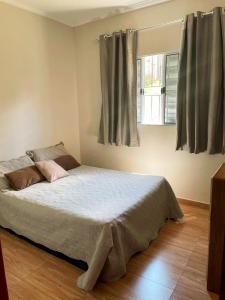 a bedroom with a large bed with two windows at Recanto da Serra in Serra Negra