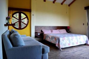 a bedroom with a bed and a couch and a chair at El Gran T'zunun in Kobén