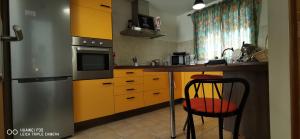 a kitchen with a refrigerator and a table with a chair at Wind Rose Duplex in Gran Tarajal