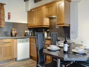 a kitchen with wooden cabinets and a table with wine glasses at Doddick Chase Cottage - Uk1363 in Threlkeld