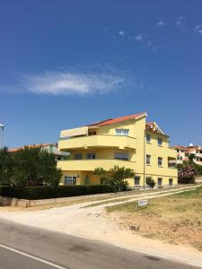 un bâtiment jaune sur le côté d'une route dans l'établissement Apartment Lara, à Vodice