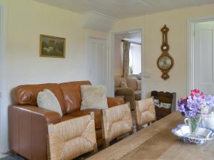 a living room with a brown leather couch and a table at Winscott Cottage in Pyworthy