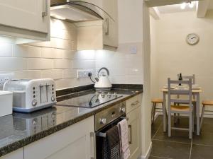 a kitchen with a sink and a stove top oven at Jasmine Cottage in Keswick