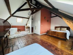a bedroom with a bed and a tub in a attic at Maison de maitre normande Etretat et Honfleur in Bolbec