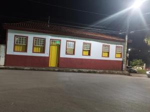 a red and white building with yellow doors on a street at Hospedaria Vó Helena in Paracatu