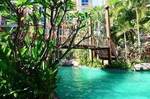 a bridge over a pool of water with trees at Pattaya Atlantis Resort Sea View Apartments in Jomtien Beach