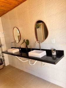 a bathroom with two sinks and two mirrors at Chalé com ventilador in Itacaré