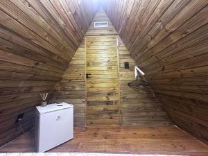 a small refrigerator in a wooden room with a ceiling at Chalé 1 in Itacaré