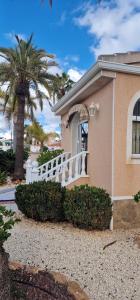 a house with a white fence and a palm tree at Casa Valdi, fantastic 4 bedroom house with private,heated swimming pool and barbecue in Ciudad Quesada