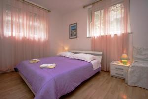 sypialnia z fioletowym łóżkiem z 2 ręcznikami w obiekcie Guest house with garden - Zuvan w Splicie