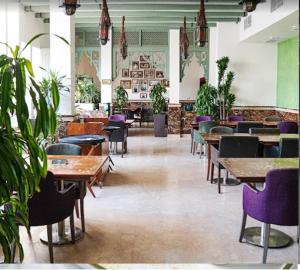 a restaurant with tables and purple chairs and plants at BHomed Shaab in Kuwait