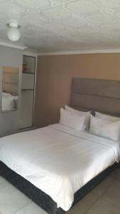 a large bed with white sheets and pillows at Emasimini Cottages in Midrand +22 photos