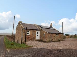 an old stone house on the side of a road at Henhill Lodge in Chathill