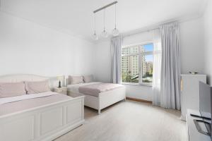 a white bedroom with two beds and a window at Bright 2 Bedroom Apartment, Beach & Pool Access in Dubai +22 photos