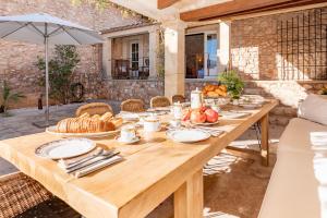 a wooden table with bread and fruit on it at Casa de Piedra ubicada en el exclusivo wine village de Viladellops, te ofrece una experiencia única, donde el lujo y la tradición se fusionan en un entorno natural privilegiado in Viladellops