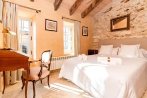 a bedroom with a bed and a desk and a piano at Casa de Piedra ubicada en el exclusivo wine village de Viladellops, te ofrece una experiencia única, donde el lujo y la tradición se fusionan en un entorno natural privilegiado in Viladellops