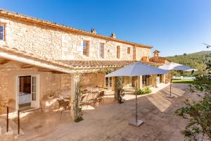 an outdoor patio with umbrellas in front of a building at Casa de Piedra ubicada en el exclusivo wine village de Viladellops, te ofrece una experiencia única, donde el lujo y la tradición se fusionan en un entorno natural privilegiado in Viladellops +37 photos
